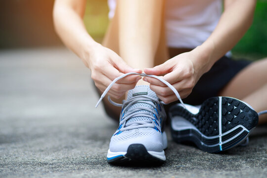 Running shoes. close up female athlete tying laces for jogging on road. Runner ties getting ready for training. Sport lifestyle. copy space banner. © methaphum