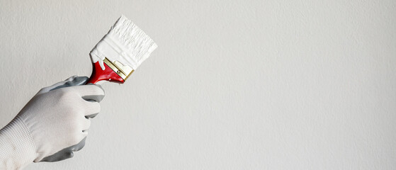 Paint brush, close up hand painter worker painting on surface wall Painting apartment, renovating with white color paint. Leave empty copy space to write descriptive text beside. - obrazy, fototapety, plakaty