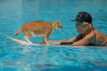 Woman teaching her cat to ride surf in ocean