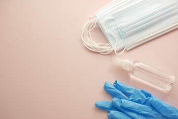 Surgical masks, thermometer and hand sanitizer on color background 