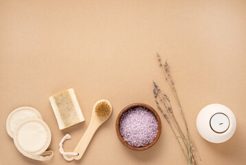 Organic sea salt for the body with dry lavender flowers, sponge, brush, soap and candle on a beige background. Skin care. The concept of a natural and eco-friendly spa product. Top view, copy space