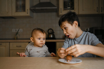 Fototapeta premium two brothers are sitting in the kitchen and eating an egg