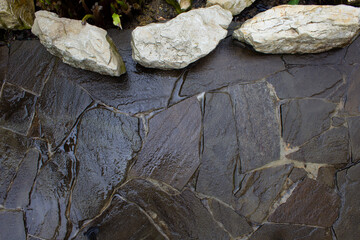 Walkway made of natural stone after the rain. Design and construction of a paved garden path. Natural stone masonry in design.