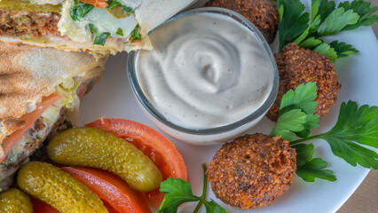 Plate of falafel with pita bread, vegetables and tzatziki sauce. Arabian meal, hummus and falafel.