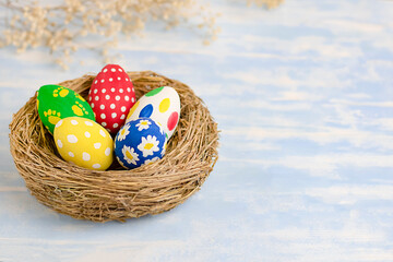 Happy easter.Easter eggs in nest and flowers on blue wooden background easter concept.With copy space