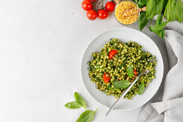 Homemade green ptitim pasta with spinach and broccoli, cherry tomatoes. Healthy dinner. Grey background. Top view. Copy space.
