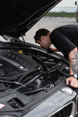 Professional driver man inspects the car and fixes problems under the hood. Guy buyer checks out the car