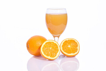 Whole and sliced oranges with a glass of squeezed juice