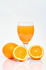 Whole and sliced oranges with a glass of squeezed juice