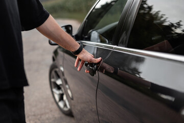 Plakat Man driver opens the door of a black car. A man's hand holds the door handle, close-up. Rent a car
