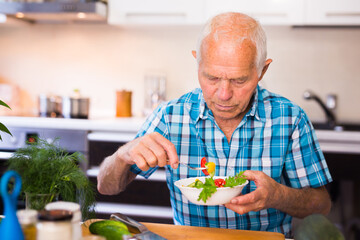 elderly man eating fresh vegetable salad at home