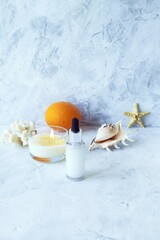 Fototapeta na wymiar Cream, citruses, aromatic oil, healthy tinctures and seashells and a burning candle on a light background, spa, natural ingredients, body care