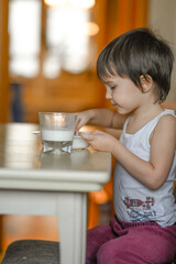 a little boy at home in the kitchen has breakfast, he eats porridge and drinks milk