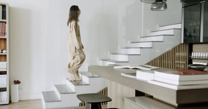 Slow Motion shot of young Caucasian freelance woman walking up stairs in her modern duplex apartment. female feet climbing the minimalist stairs. Barefoot Woman Going Up a modern Staircase