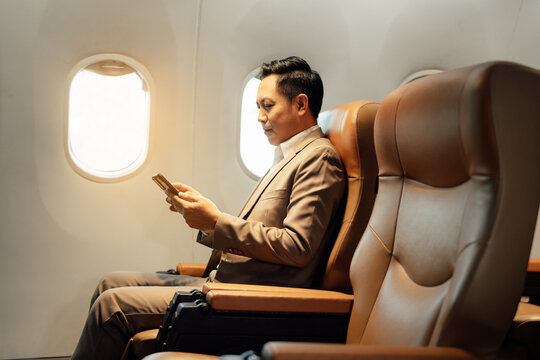 Businessman using smartphone while sitting in airplane, Traveling and technology. Flying at first class.