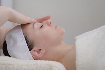 Woman receiving head massage. Calm patient woman undergoing the cosmetic facial massage procedures for rejuvenation skin face