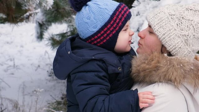 Mother and son kiss in nature, snow-covered winter forest