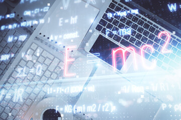 Physics and math theme hologram with formula drawings over computer on the desktop background. Top view. Multi exposure. Concept of education.