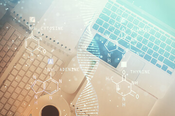 DNA hologram drawings over computer on the desktop background. Top view. Multi exposure. Concept...