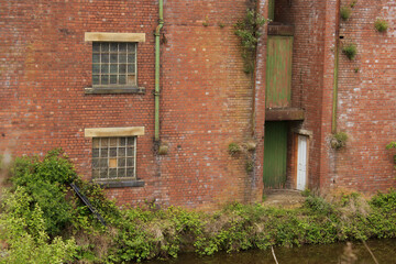 Fototapeta na wymiar Doors of an old red brick warehouse in Shipley Yorkshire open directly on to the canal where once boats would have moored to load and unload cargo