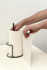 hand holds a paper towel roll on a metal holder