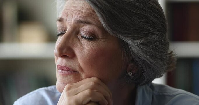 Close up face brooding older businesswoman staring aside feel concerned or exhausted take break at workplace, looking deep in thoughts. Pensive mature female thinking, ponders alone sit indoor concept