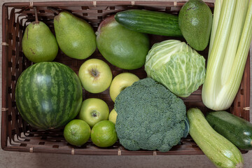 Rectangular basket with green fruit and vegetables: watermelon, apple, pear, mango, lime, cabbage