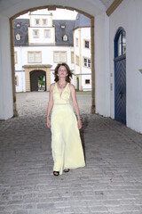 attractive woman in an evening dress walks through a gate in the neuhaus castle near paderborn