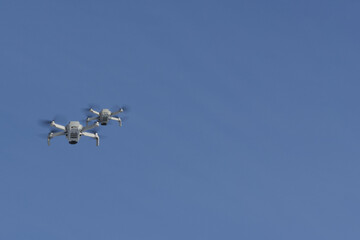 Two modern Remote Control Air Drones Fly with action cameras in blue sky. Modern technologies. Close up. Travel, hobby, inspiration.