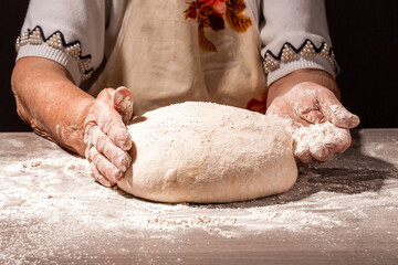 Bread in the old wrinkled hands of the grandmother close-up. Grandmas bread dough. Grandmother...