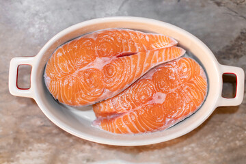 Two steaks of fresh salmon in a white baking dish. Raw red fish steak. Delicacy.
