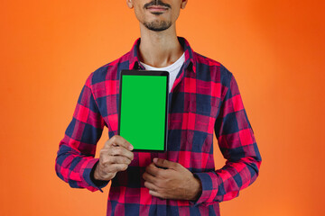 Black Man With Junina Party Outfit holding a tablet Isolated on Orange Background.