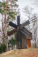 Old wooden mill. Landscape with an old windmill against the background of clouds and forest.