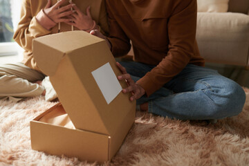 Closeup image of young man opening box with present her ordered online for girlfriend
