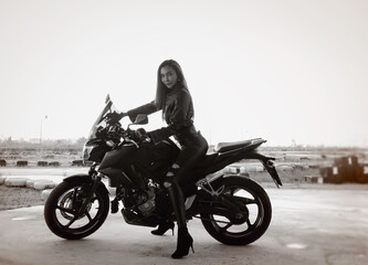 Fototapeta na wymiar Beautiful woman posing wearing black suit,posing with motorcycle