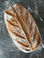 whole grain wheat bread made with sour dough on grey surface with ear pattern in bread crust