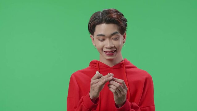 Asian Transgender Guy Applying Lipstick In The Green Screen Studio
