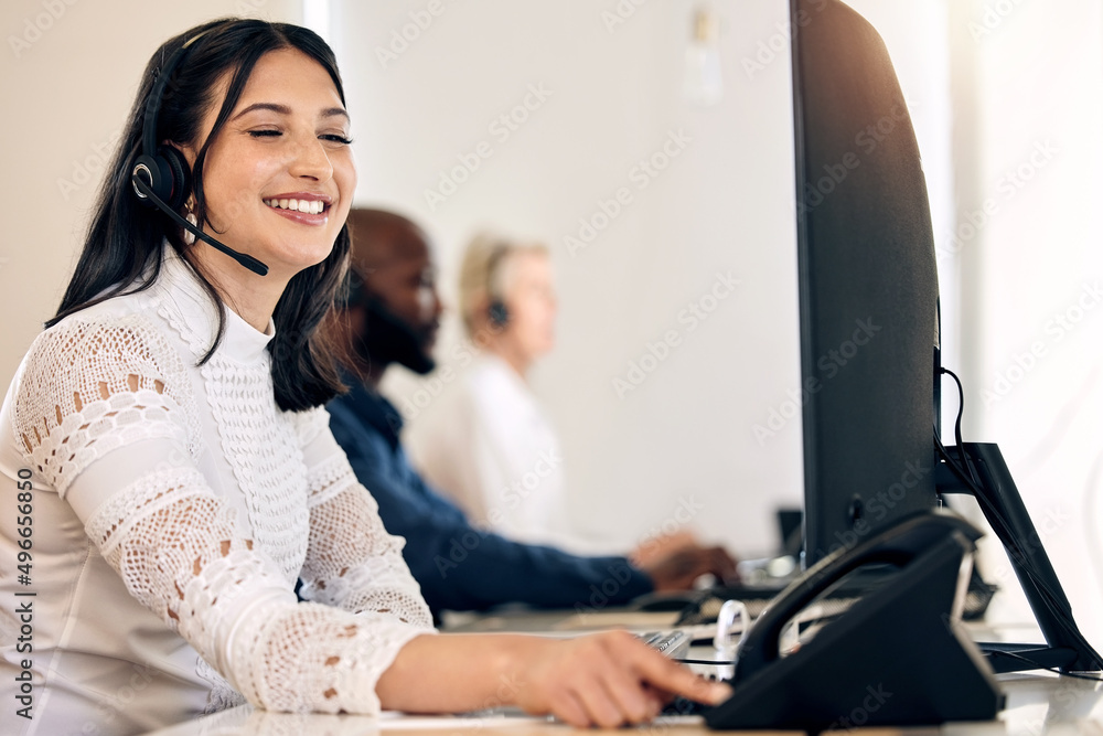 Aufkleber Ill call the customer right away to deliver the good news. Shot of a young call centre agent using a telephone while working on a computer in an office.