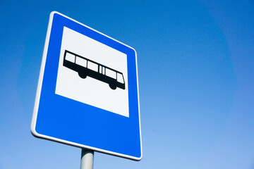 Bus stop road sign. Blue, white and black information sign. Traffic sign isolated on blue sky. Long...