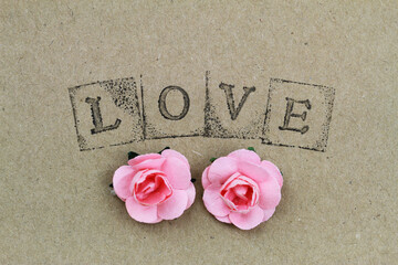 Word love made with letter stamps and two pink paper roses

