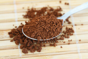 Instant coffee on spoon on bamboo mat, closeup
