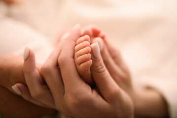 Obraz na płótnie Canvas Woman holding her newborn baby feet in her hand