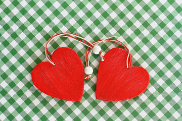 Two red wooden hearts on white and green checkered background with copy space
