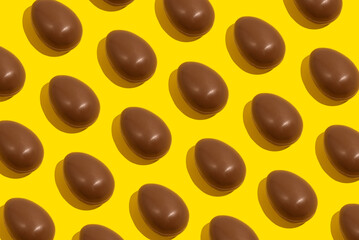 Chocolate eggs. Easter eggs. Seamless pattern of whole chocolate eggs on a yellow background. Easter sweet chocolate background