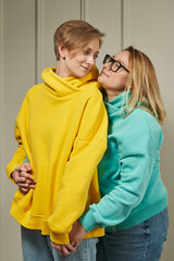 Obraz premium two beautiful women. lgbt couple in colored sweatshirts look at each other with tenderness