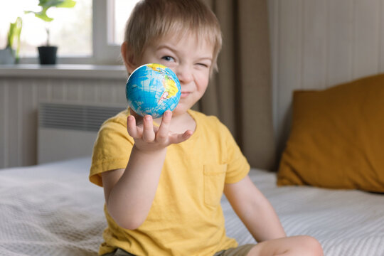 Child boy with blonde hair hugging the earth globe, save the earth concept. 3 years old kid holding a toy globe model. Baby toddler. Early, age children education development.