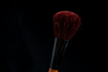 make-up brush with powder of different colors on a dark background like space dust