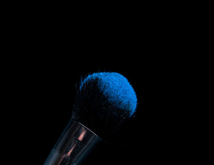 make-up brush with powder of different colors on a dark background like space dust