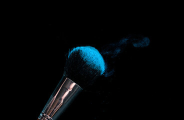 make-up brush with powder of different colors on a dark background like space dust