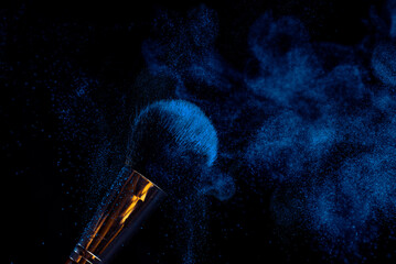 make-up brush with powder of different colors on a dark background like space dust